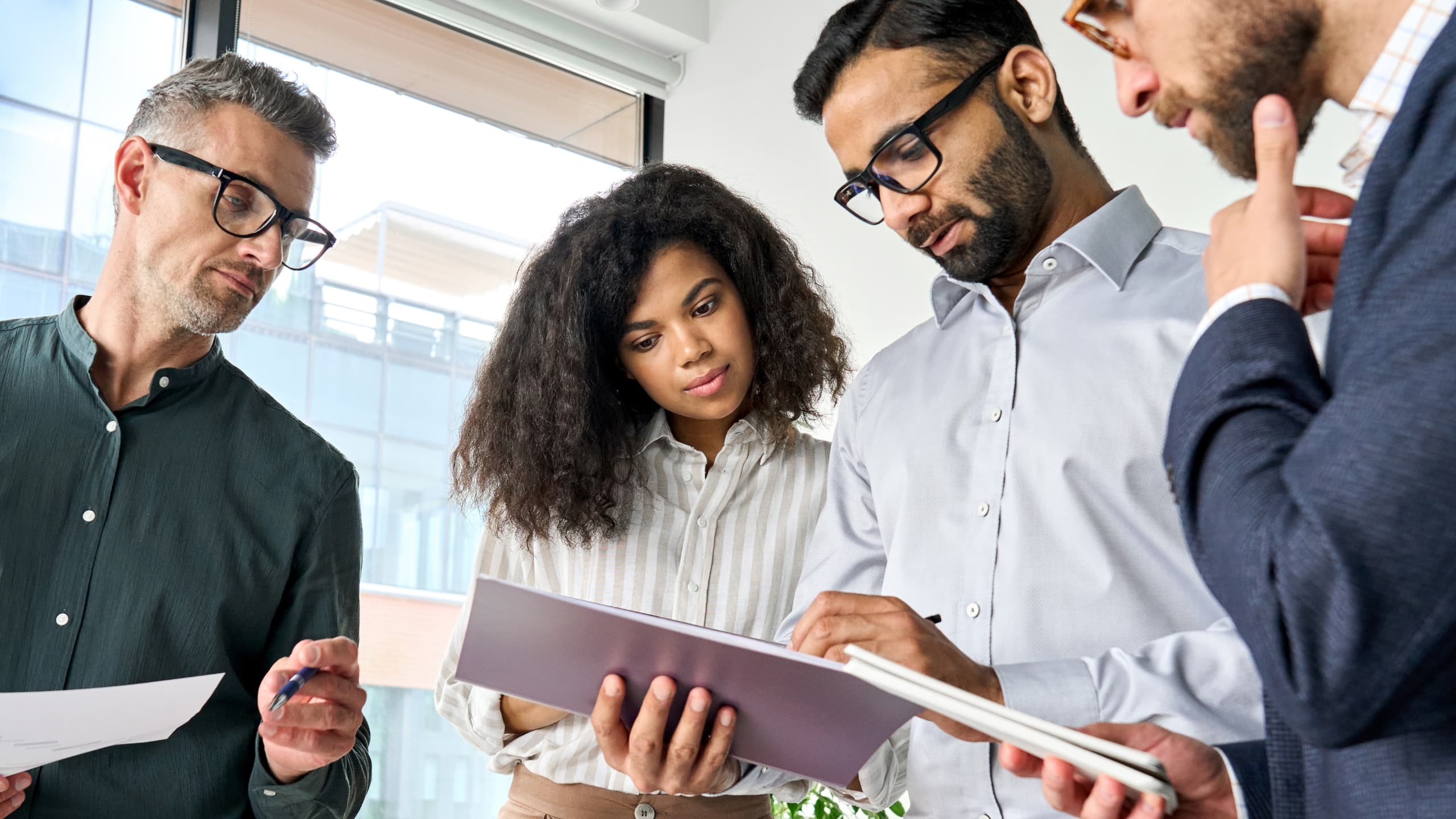 Four people in an office, discussing a document.