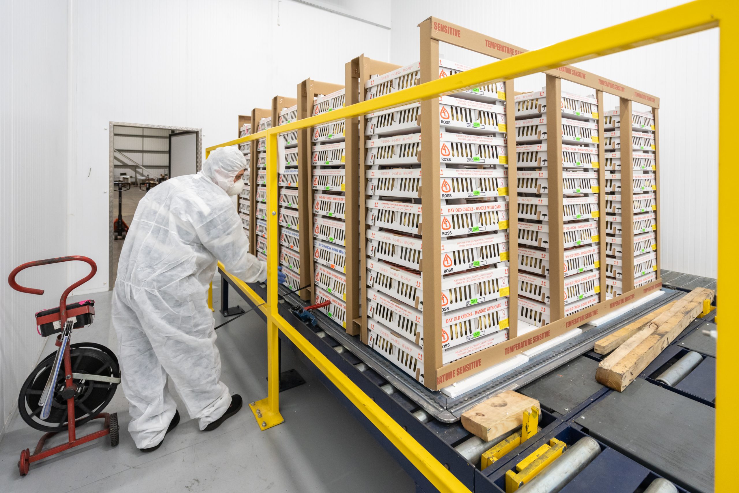 Person in protective gear handling stacked boxes in an industrial setting.