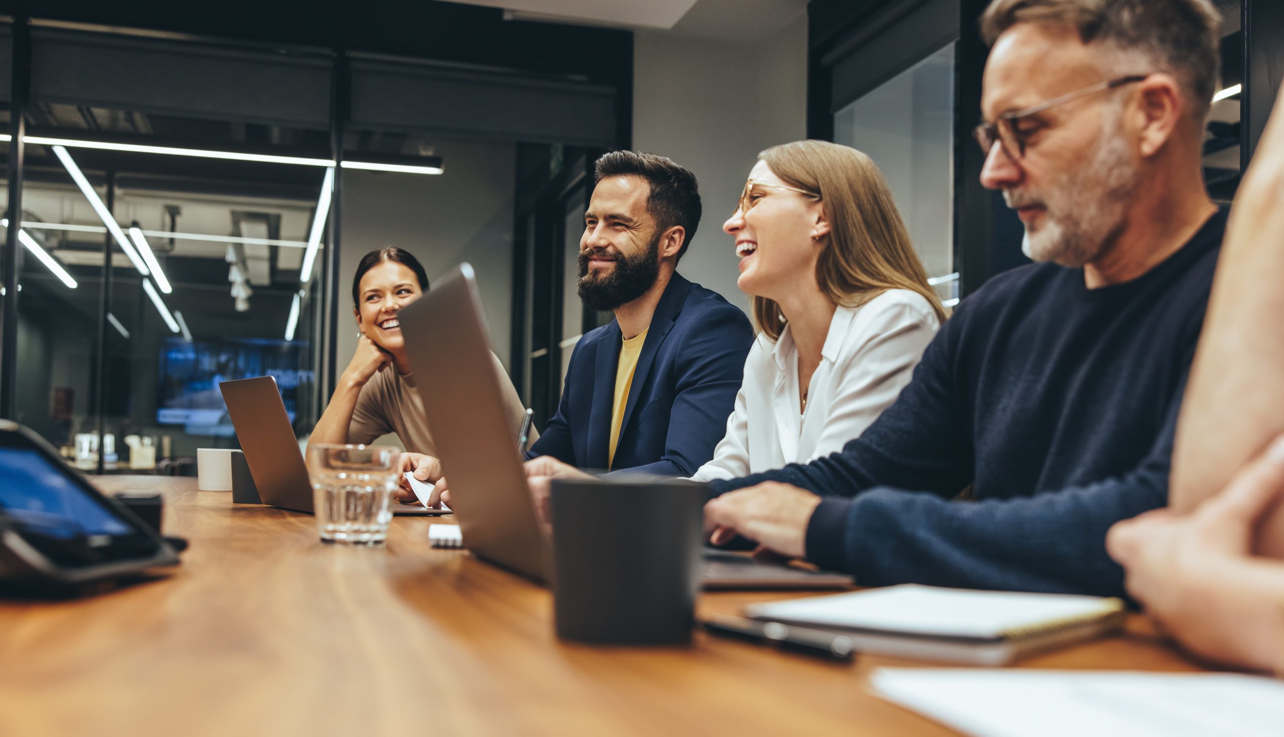 A group of four people in a meeting around a conference table in an office.