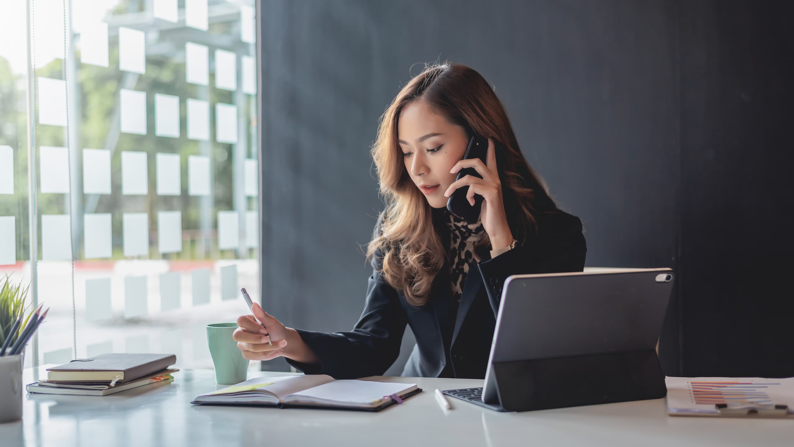 Person on phone and writing in notebook.