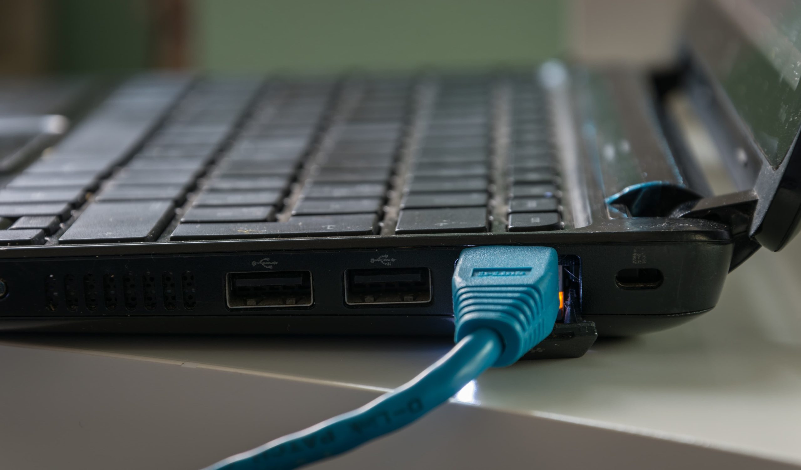 Close-up of a laptop's side with USB ports and an Ethernet cable connected.