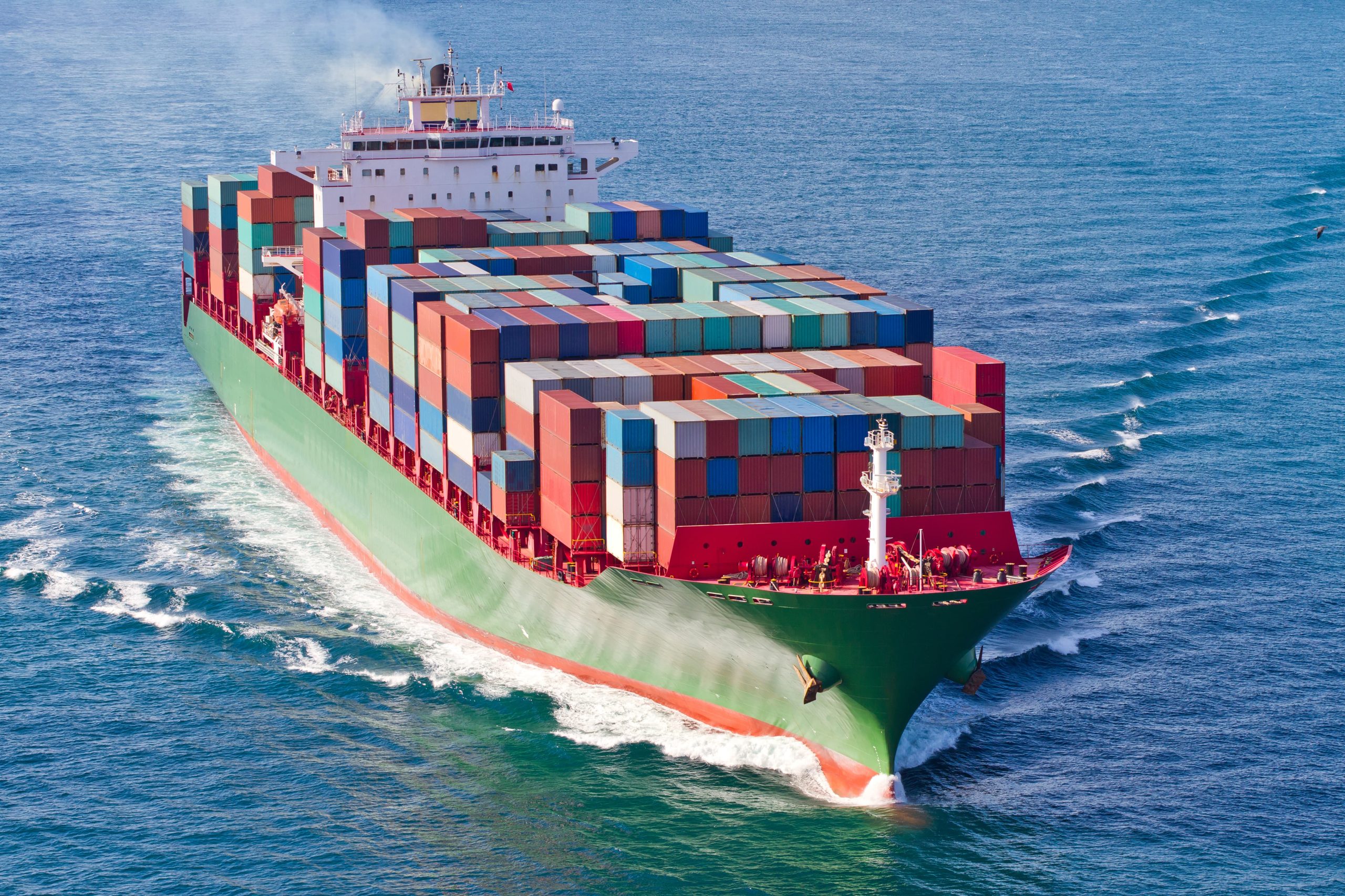 Large cargo ship with multicolored containers sailing in open sea.