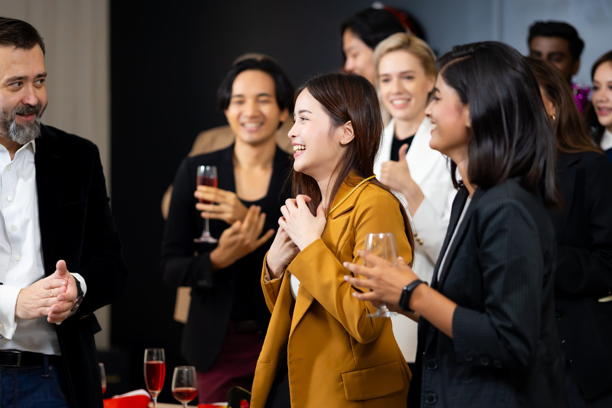 A group of people in formal attire smiling and interacting at a social gathering.