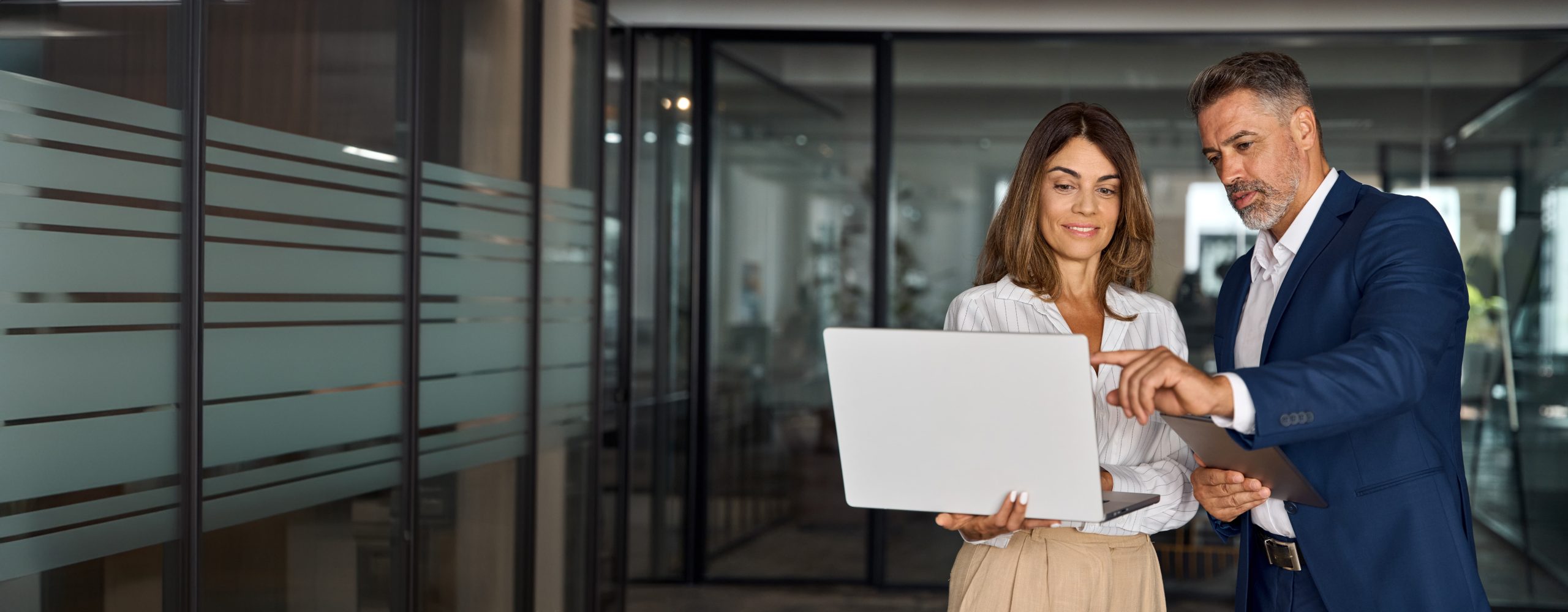 Two people in an office, discussing something on a laptop.