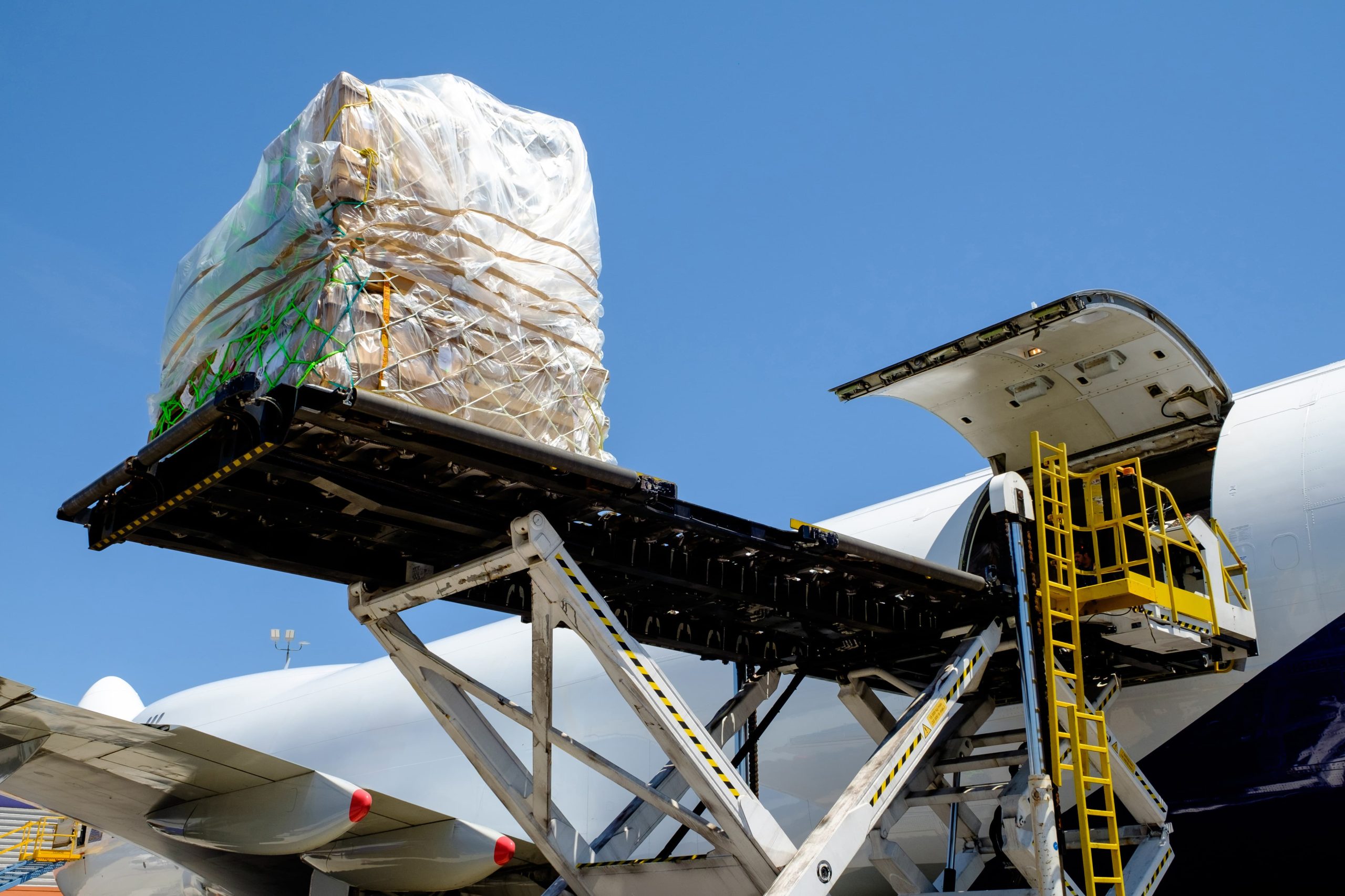 Cargo wrapped in plastic being loaded onto an aircraft with a mechanized lift.