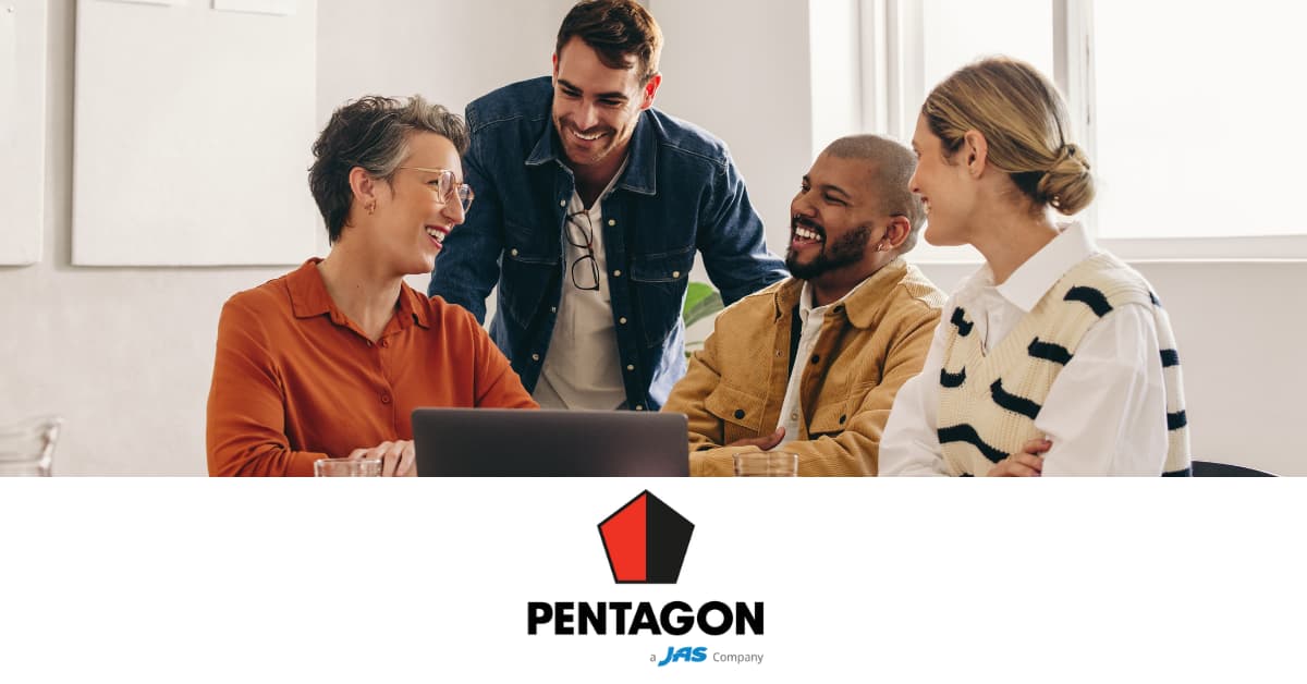 Four people in an office setting discussing around a table with a laptop and a Pentagon logo below.